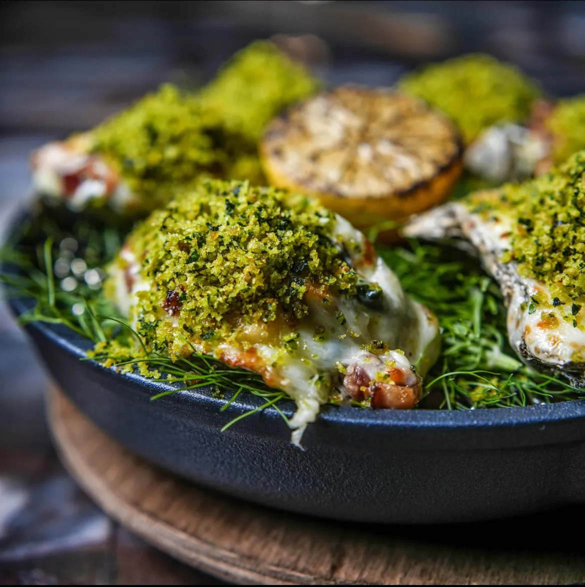 Grilled oysters under a herb crust with charred lemon