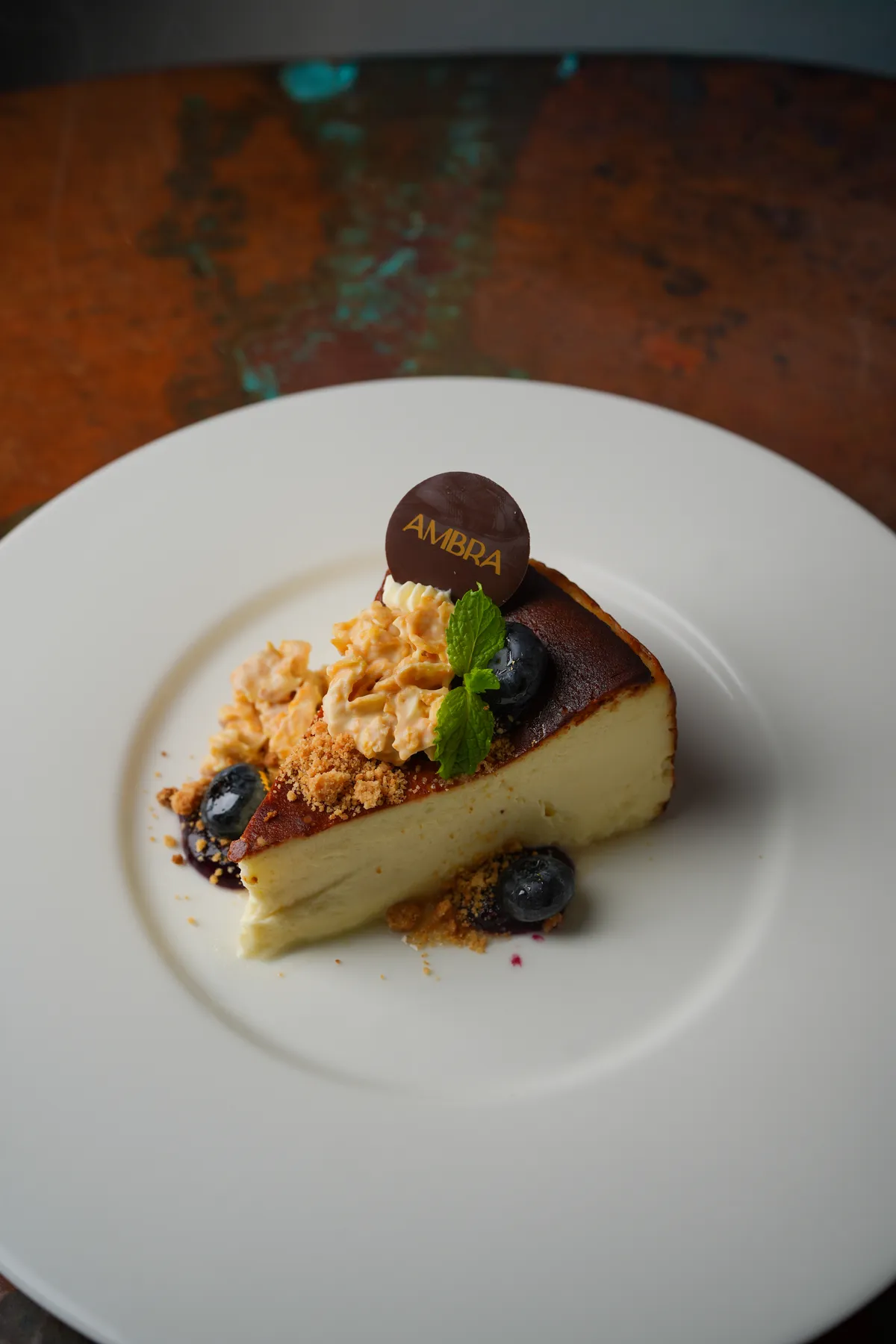 Slice of burnt Basque cheesecake with an Ambra chocolate medallion