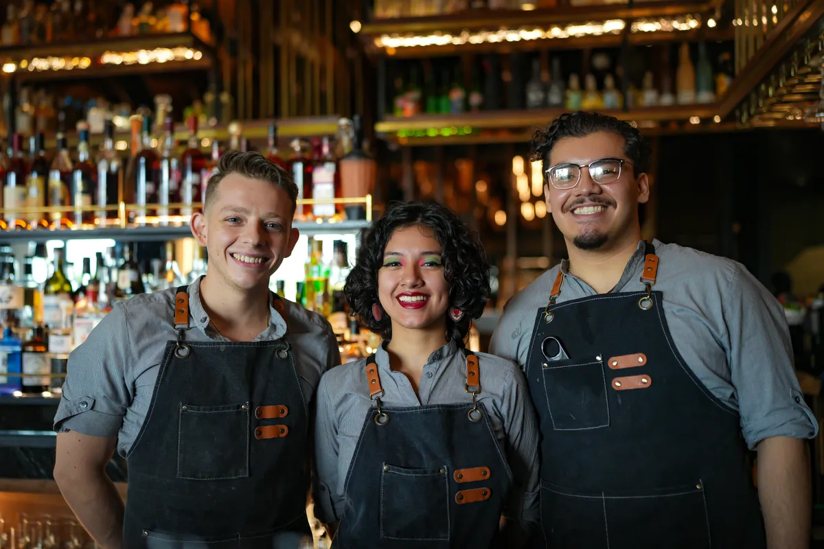Ambra's bar team in denim aprons behind the bar