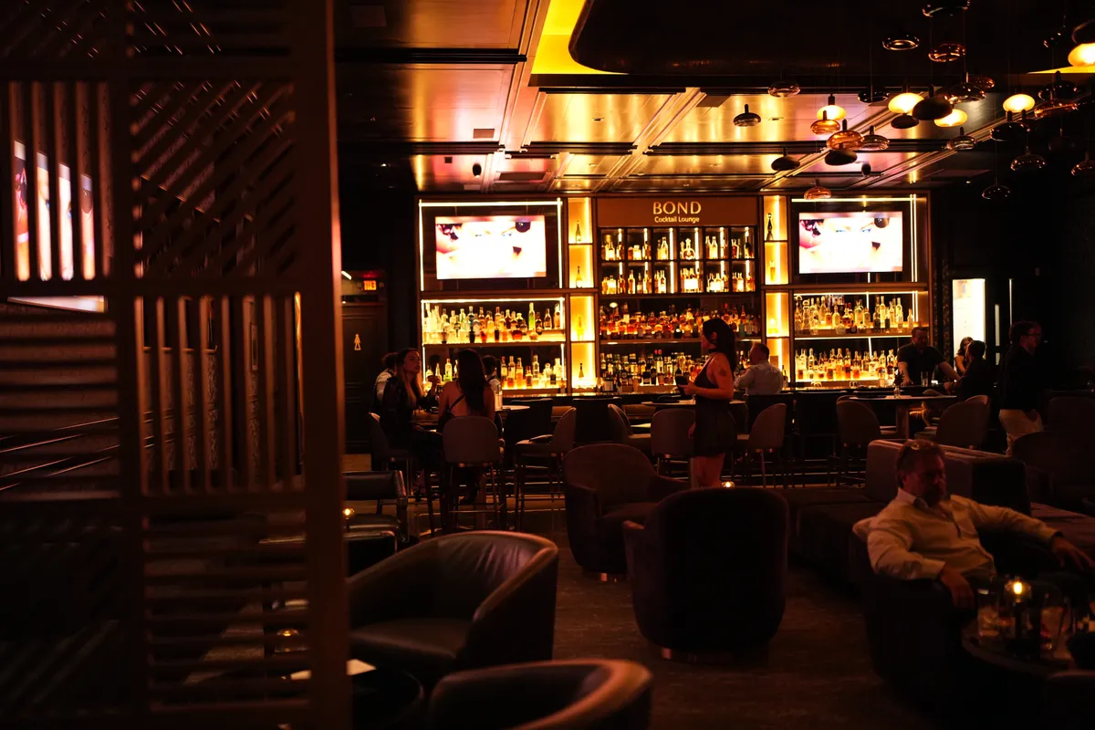 Guests in the low-lit lounge at Bond with the bar glowing behind