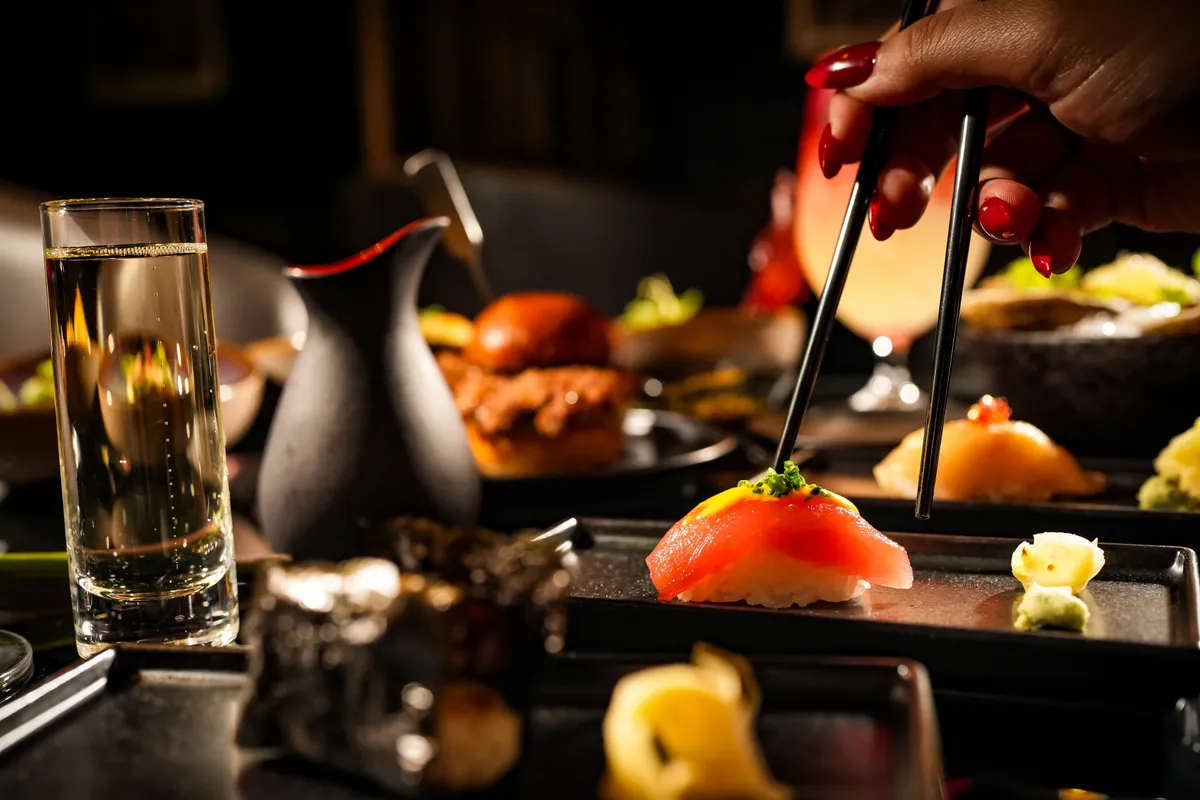 Torched tuna bites lifted with chopsticks over a slate plate
