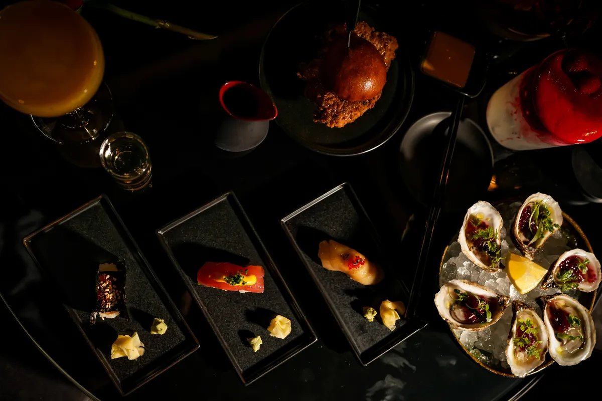 Overhead of oysters, luxury bites and cocktails on Bond's black tables