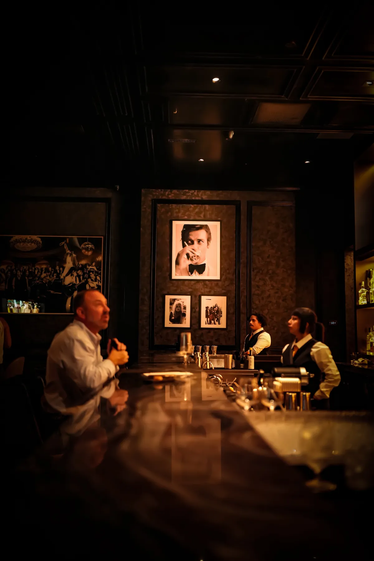 Bartenders at work beneath the framed Bond portrait