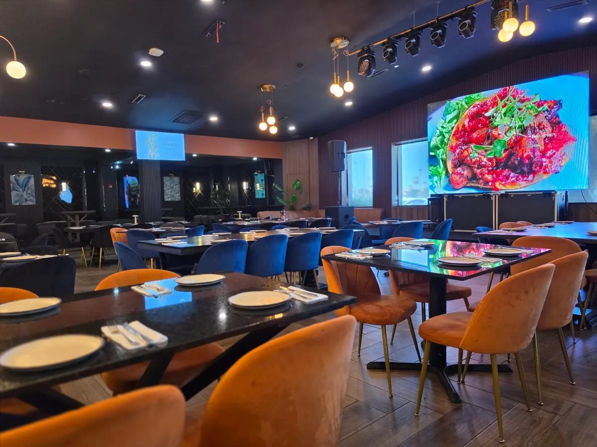 Camaleón's dining room with velvet chairs and the LED video wall