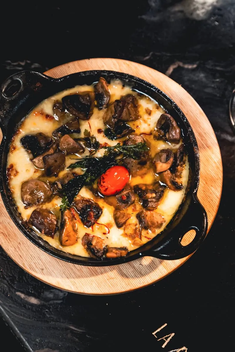 Queso fundido with mushrooms bubbling in a cast-iron skillet