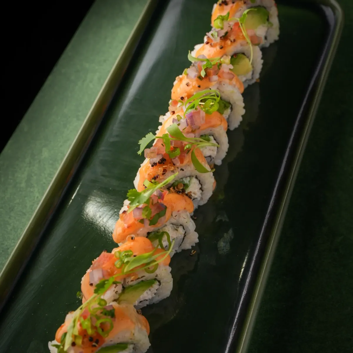 Salmon and avocado roll on a green ceramic plate