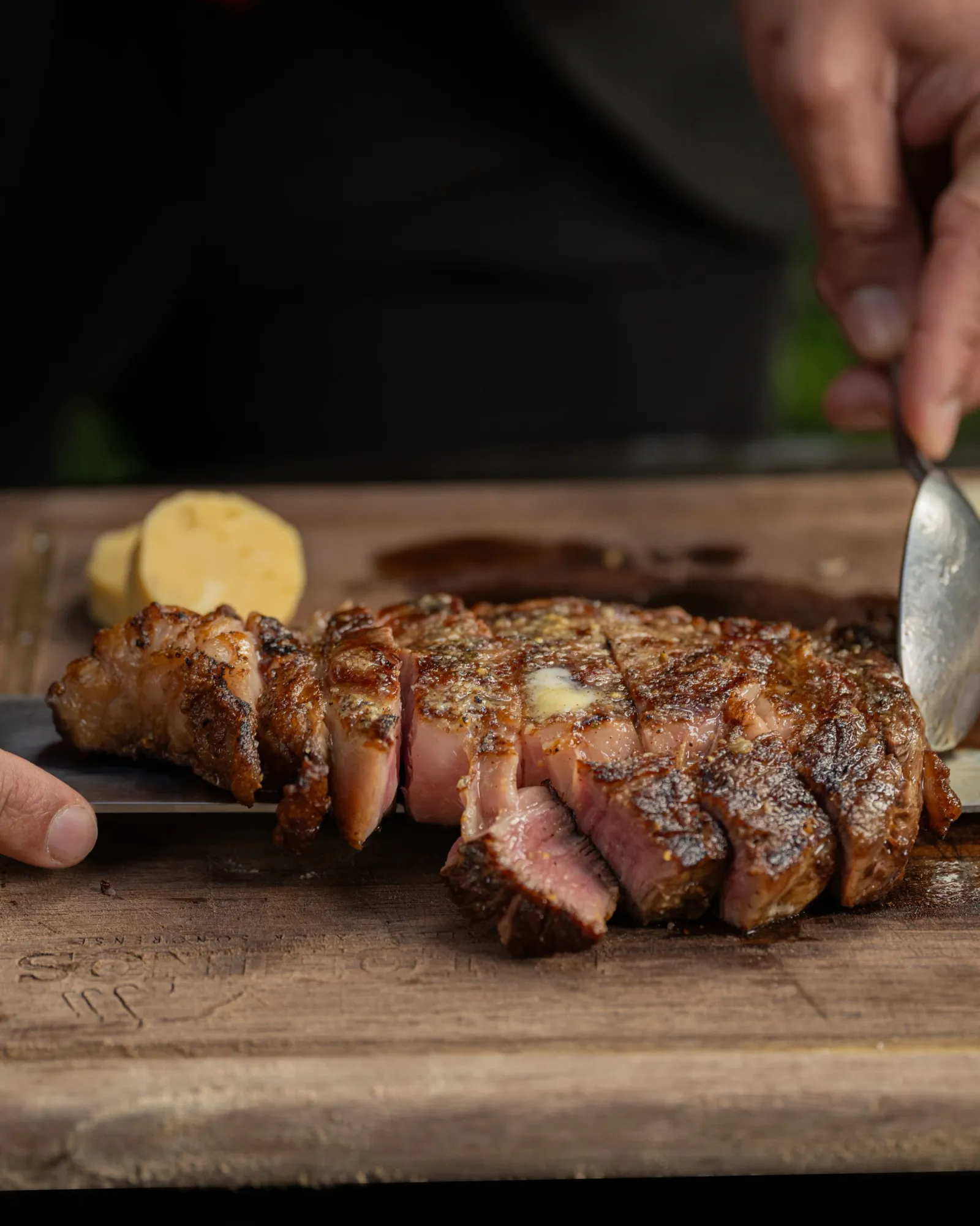 Sliced Sonoran-style ribeye with compound butter on a wooden board at Palominos McAllen
