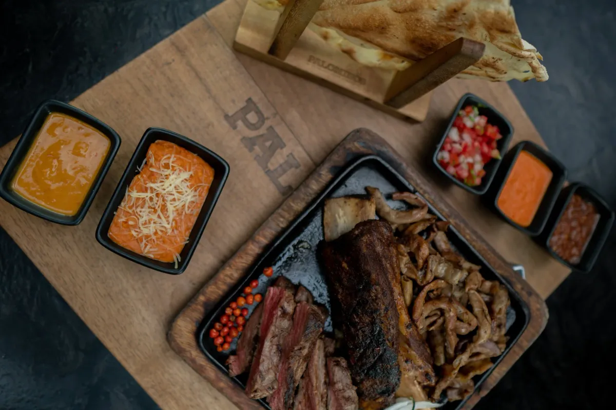 Carne asada board with flour tortillas, beans and salsas