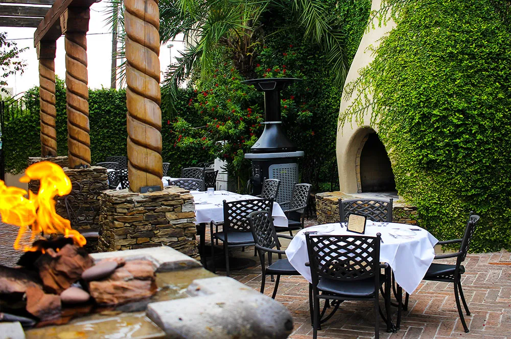 Santa Fe Steakhouse's garden patio at dusk with its stone fireplace lit, McAllen