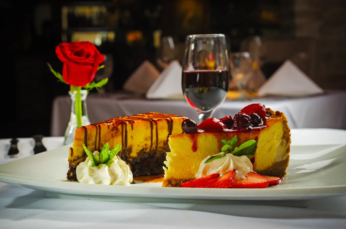 Cheesecake with berry compote and a single red rose on the table