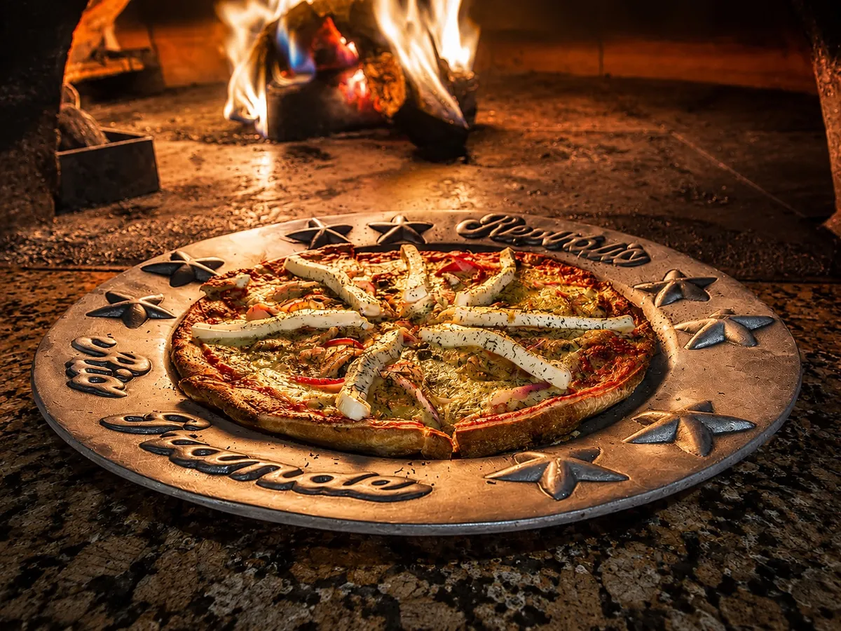 A pizza fresh from the brick oven on a Republic-stamped pan
